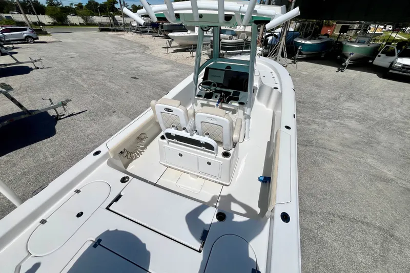 Slide: The Image of 2022 Blue Wave 2800 Pure Hybrid boat interior with console and seating, parked outdoors. - 12