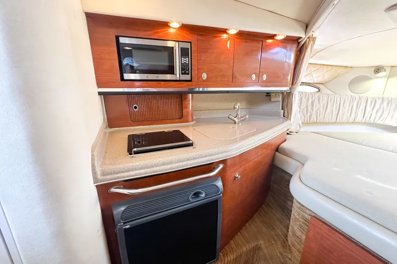 Slide: The Image of 2006 Sea Ray 290 Amberjack interior with kitchenette, featuring microwave, sink, and compact fridge. - 15