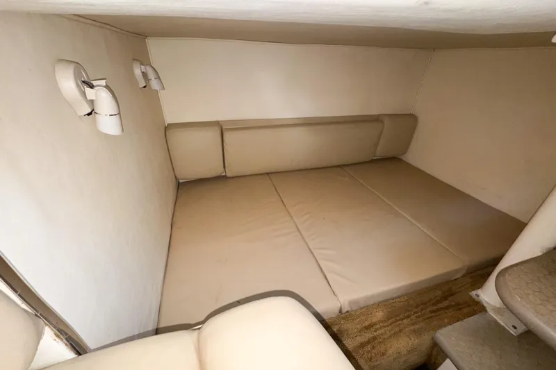 Slide: The Image of 2006 Sea Ray 290 Amberjack cabin interior with beige cushions and wall-mounted lights. - 21