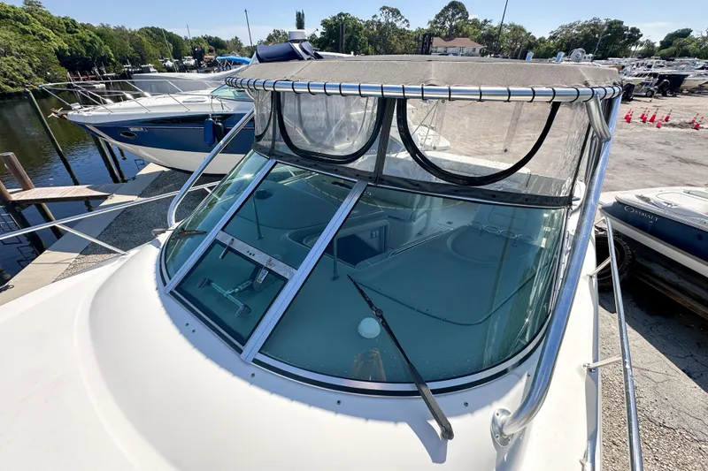 Slide: The Image of 2006 Sea Ray 290 Amberjack boat docked, featuring a clear windshield and canopy. - 31