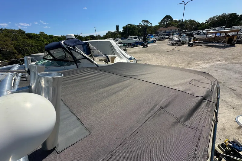 Slide: The Image of 2006 Sea Ray 290 Amberjack boat covered, parked in a marina under clear blue sky. - 33