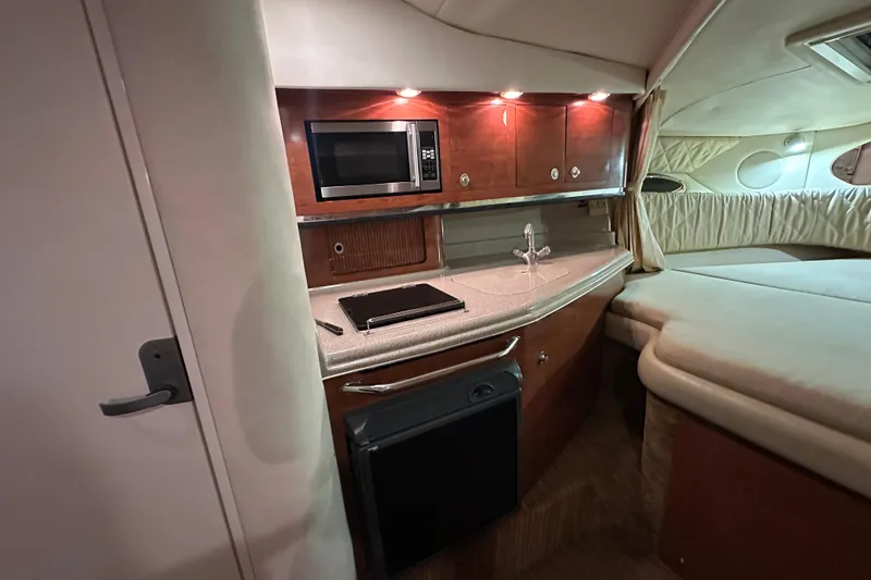 Slide: The Image of 2006 Sea Ray 290 Amberjack cabin interior with kitchenette, microwave, and cozy sleeping area. - 43