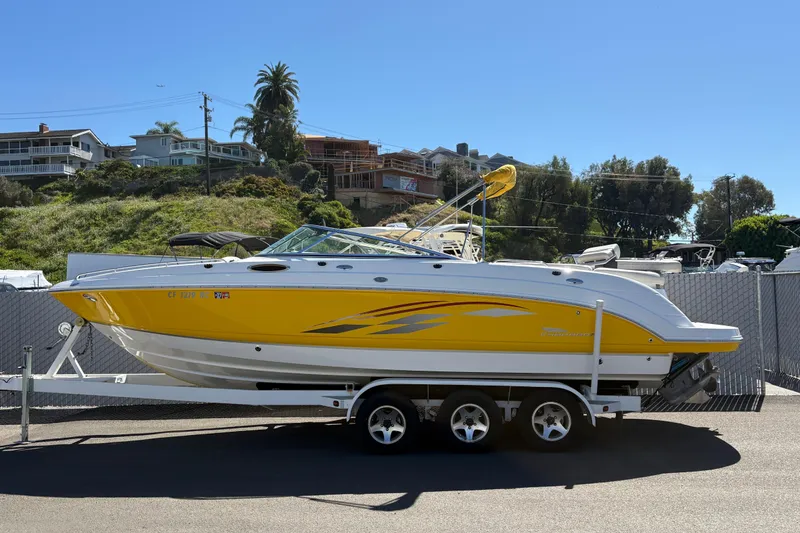The Image of 2004 Chaparral 256 SSi boat in vibrant yellow on a trailer, parked outdoors. - 0