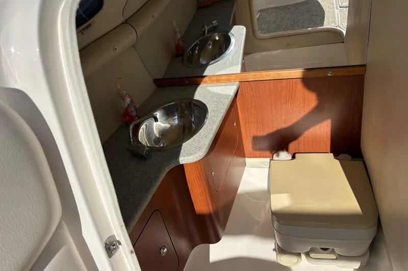 Slide: The Image of 2004 Chaparral 256 SSi boat interior with sink, countertop, and portable toilet. - 8
