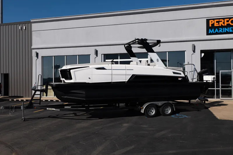 Slide: The Image of 2025 Balise Helix 24C boat on trailer outside marine dealership. - 2