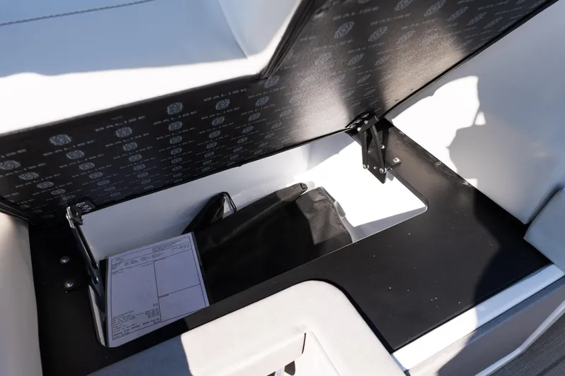 Slide: The Image of Open storage compartment in 2025 Balise Helix 24C boat, showing documents and bag. - 27