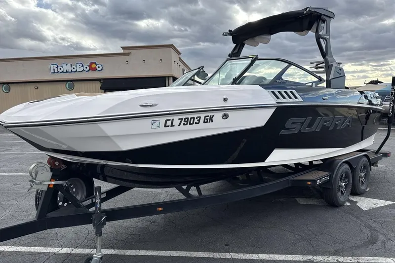 The Image of 2018 Supra SA 550 boat on trailer in parking lot, cloudy sky background. - 1