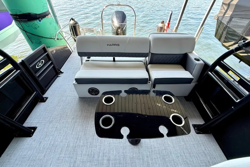 Slide: The Image of Interior of 2022 Harris Sunliner 250 boat with seating and table on water. - 18