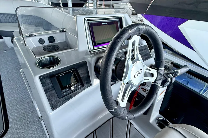 Slide: The Image of 2022 Harris Sunliner 250 boat dashboard with steering wheel and modern controls. - 21