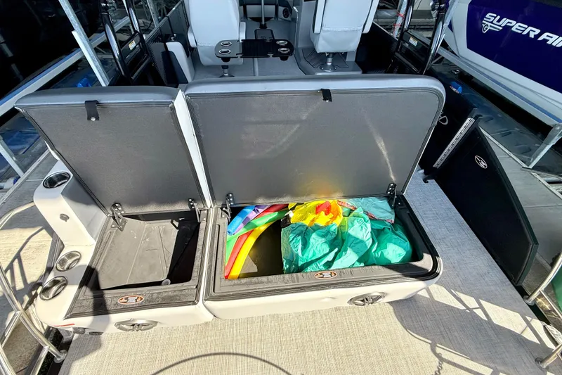 Slide: The Image of Open storage compartments on a 2022 Harris Sunliner 250 boat, revealing colorful items inside. - 27