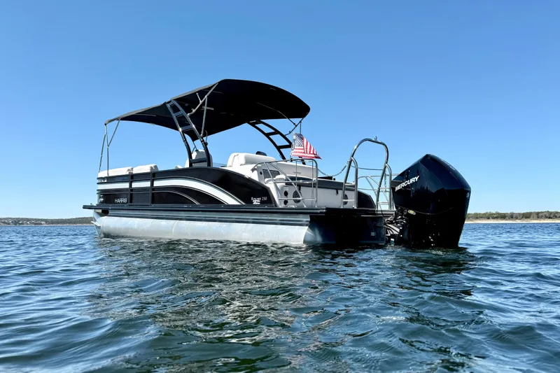 Slide: The Image of 2022 Harris Sunliner 250 pontoon boat on water, featuring a sleek black design. - 3