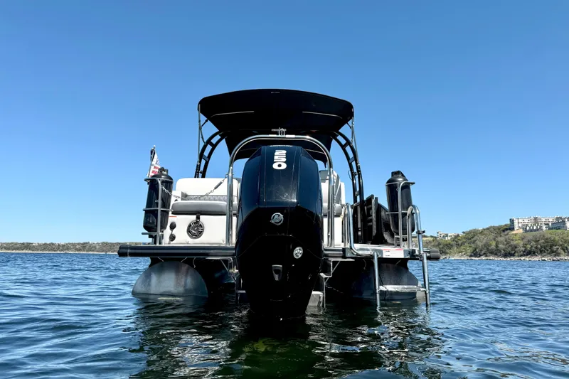 Slide: The Image of 2022 Harris Sunliner 250 pontoon boat on a lake under clear blue sky. - 4