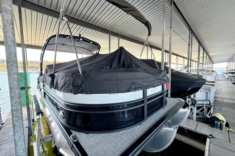 Slide: The Image of 2022 Harris Sunliner 250 pontoon boat docked under a covered marina. - 8