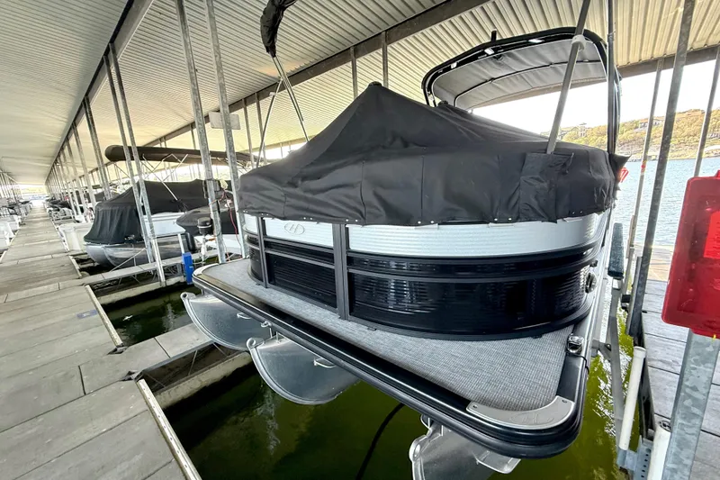 Slide: The Image of 2022 Harris Sunliner 250 pontoon boat docked with cover in marina. - 9