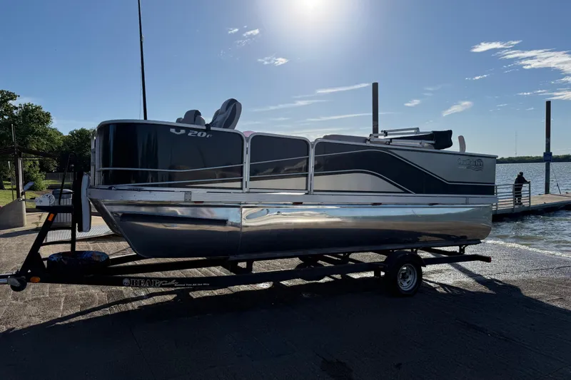 Slide: The Image of 2018 SunCatcher V20 Fish pontoon boat on trailer by a lake under clear sky. - 24