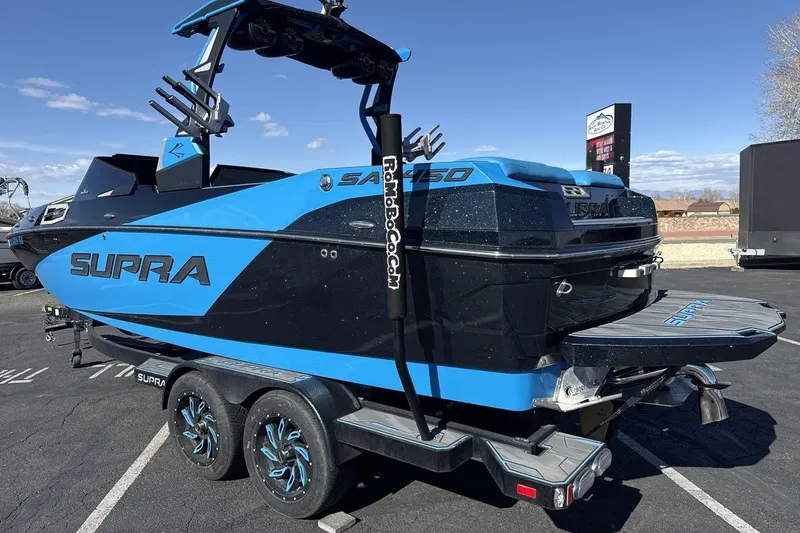 Slide: The Image of 2021 Supra SA 450 boat on trailer, blue and black design, parked outdoors. - 3