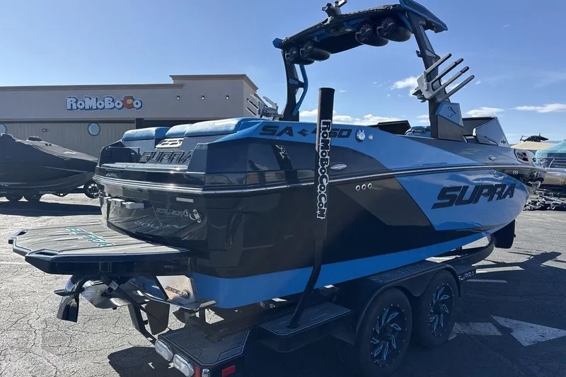 Slide: The Image of 2021 Supra SA 450 boat in parking lot, blue and black design, on trailer. - 5
