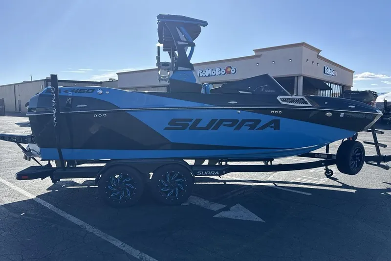 Slide: The Image of 2021 Supra SA 450 boat on trailer, blue and black design, parked outdoors. - 6