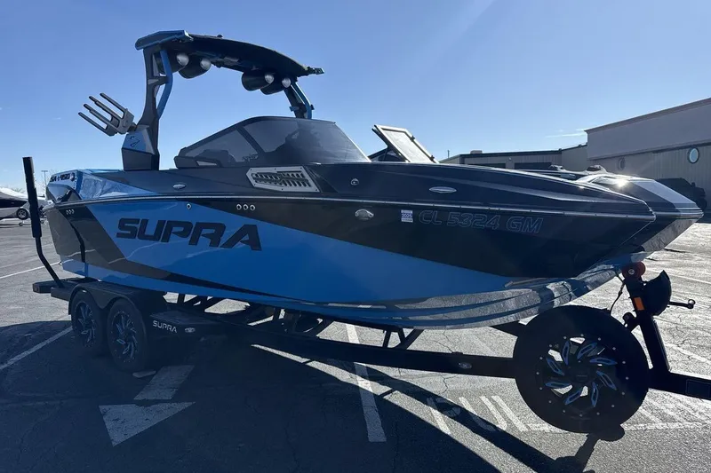 Slide: The Image of 2021 Supra SA 450 boat on trailer, blue and black design, parked outdoors. - 7