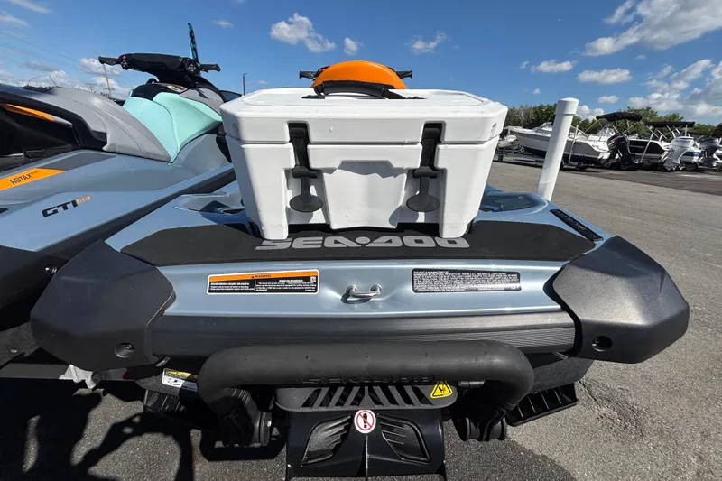 Slide: The Image of 2023 Sea-Doo GTI 130 with cooler, parked outdoors under a clear blue sky. - 16