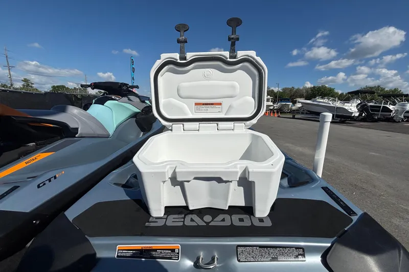 Slide: The Image of 2023 Sea-Doo GTI 130 with open storage compartment, parked outdoors under blue sky. - 43