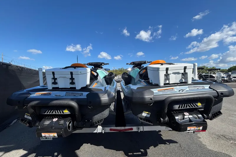Slide: The Image of 2023 Sea-Doo GTI 130 jet skis on trailer under clear blue sky. - 7