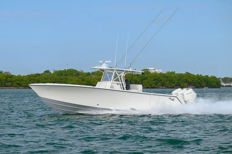 The Image of 2024 SeaVee 370Z boat cruising on water with fishing rods, clear sky, and lush greenery. - 1