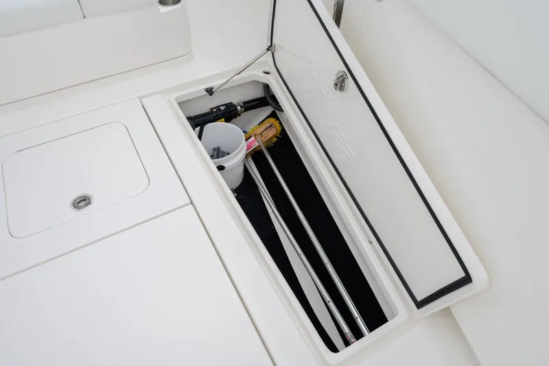 Slide: The Image of Open storage compartment on 2024 SeaVee 370Z boat, containing rods and a bucket. - 22