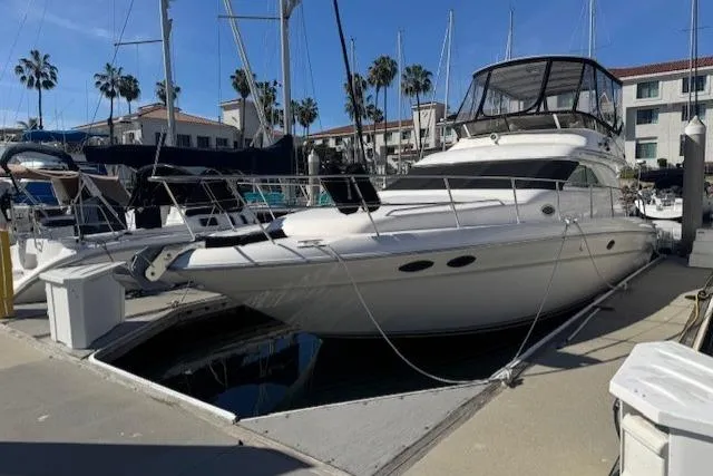The Image of 1996 Sea Ray 400 Sedan Bridge yacht docked at marina under clear blue sky. - 0