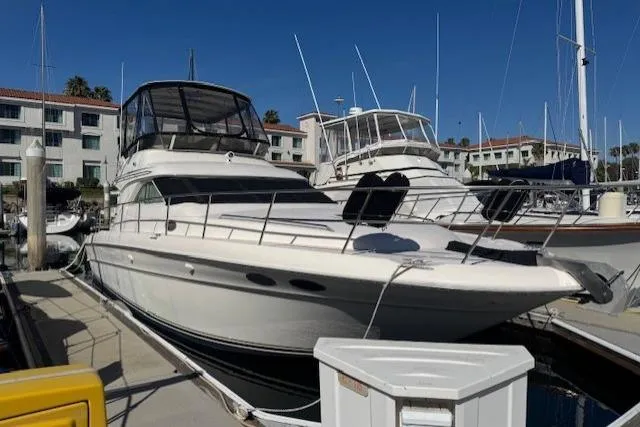 Slide: The Image of 1996 Sea Ray 400 Sedan Bridge yacht docked at marina under clear blue sky. - 1