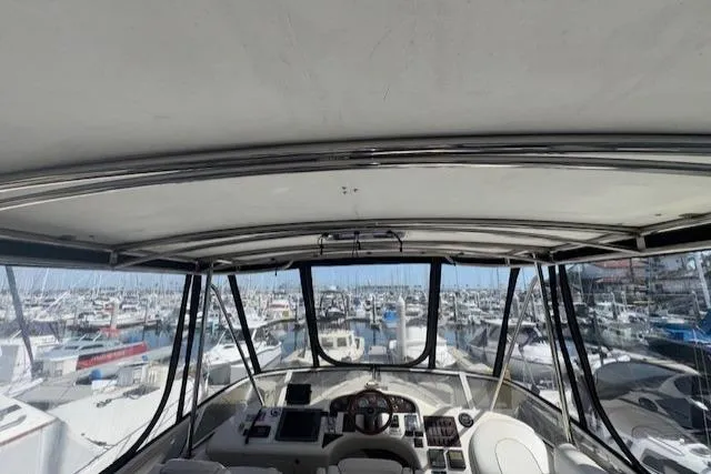 Slide: The Image of 1996 Sea Ray 400 Sedan Bridge helm with white seating and marina view. - 20