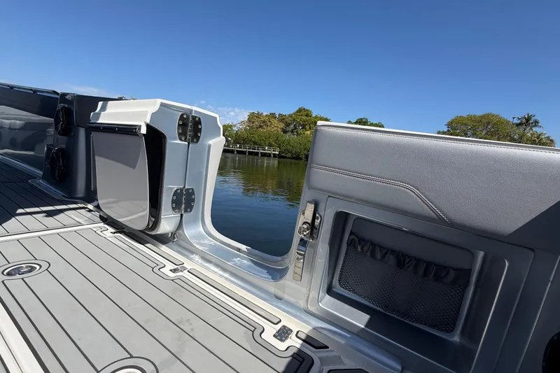 Slide: The Image of 2018 Nor-Tech 390 Sport Center Console boat interior with open side door, docked by water. - 11