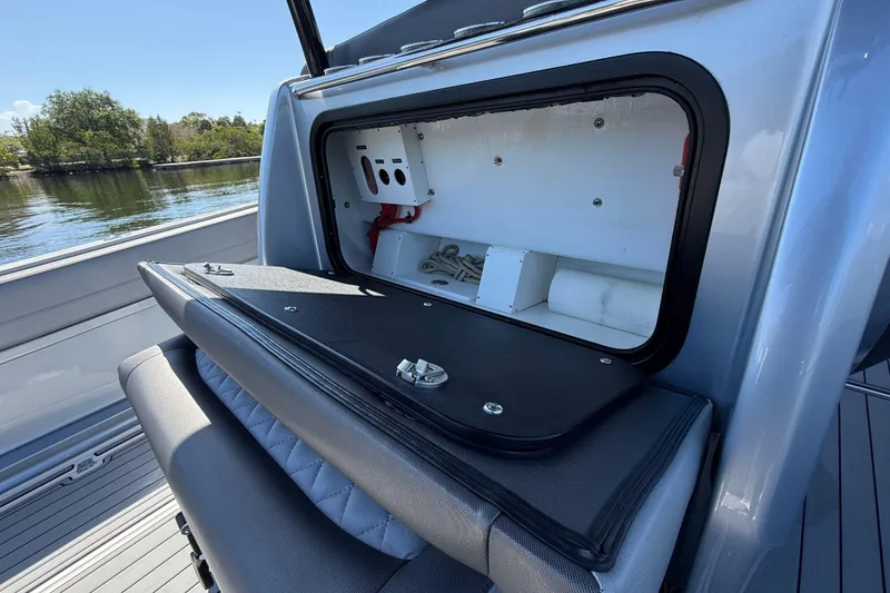 Slide: The Image of 2018 Nor-Tech 390 Sport Center Console storage compartment open on a sunny day. - 13