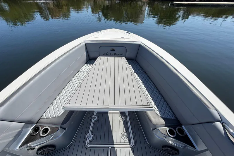 Slide: The Image of 2018 Nor-Tech 390 Sport Center Console boat interior with sleek seating and table on calm water. - 19