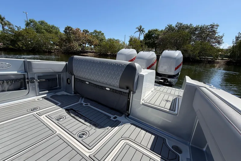 Slide: The Image of 2018 Nor-Tech 390 Sport Center Console boat with triple Mercury engines, docked by lush greenery. - 9