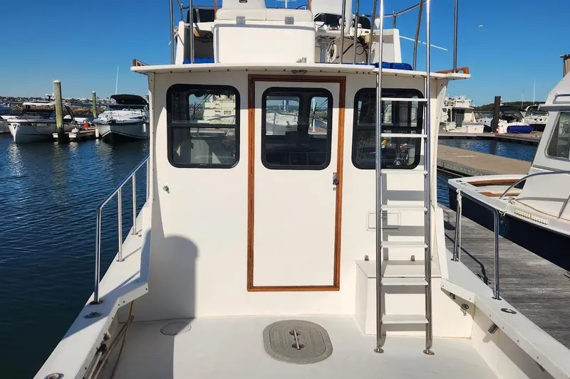 Slide: The Image of 2001 Eastern 31 Casco Bay Flybridge boat docked at marina, rear view with ladder. - 3