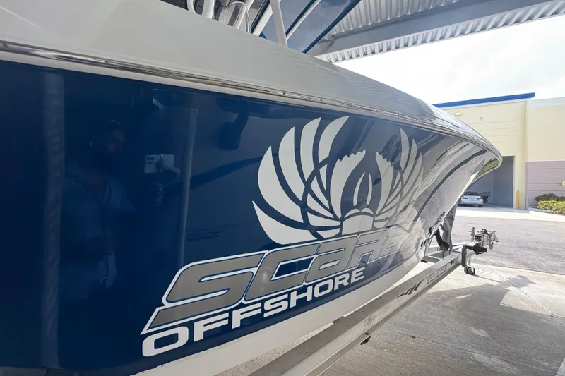 Slide: The Image of 2023 Wellcraft 242 Fisherman boat with Scarab Offshore branding in a covered area. - 18