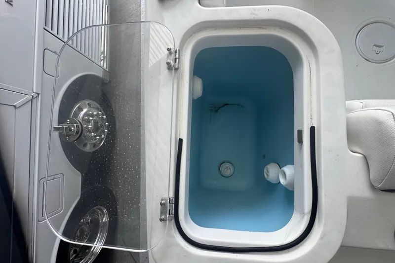 Slide: The Image of Open storage compartment on 2023 Wellcraft 242 Fisherman boat, featuring a blue interior. - 21