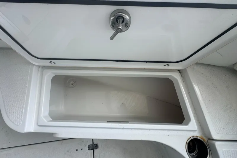 Slide: The Image of Open storage compartment on 2023 Wellcraft 242 Fisherman boat, featuring a secure latch. - 49