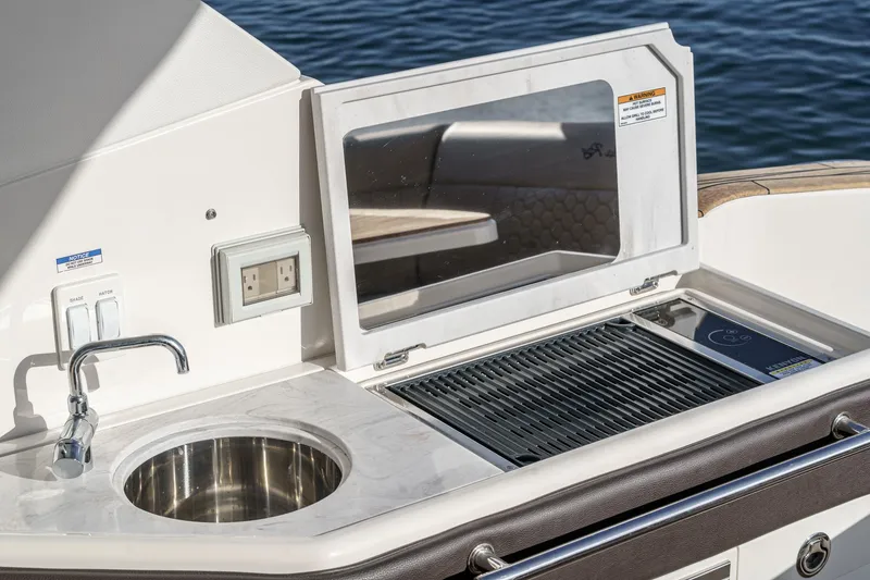 Slide: The Image of 2023 Sea Ray Sundancer 320 OB boat kitchenette with sink and grill by the water. - 19