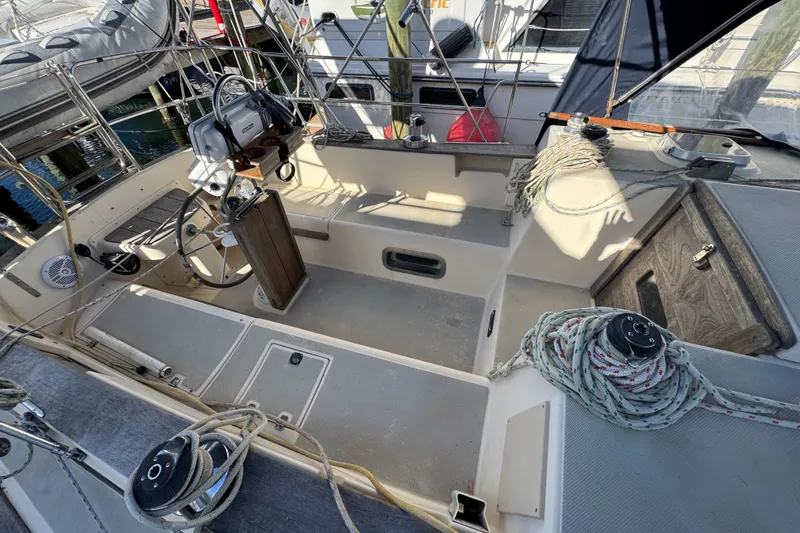 Slide: The Image of 1991 Island Packet Yachts 38 cockpit with steering wheel and ropes, docked at marina. - 11
