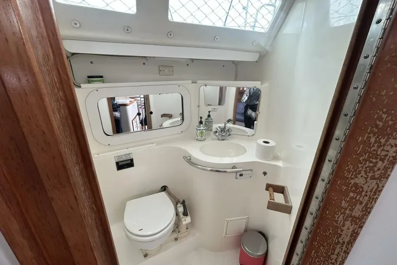 Slide: The Image of 1995 Catalina 320 yacht bathroom with toilet, sink, mirror, and wooden accents. - 17