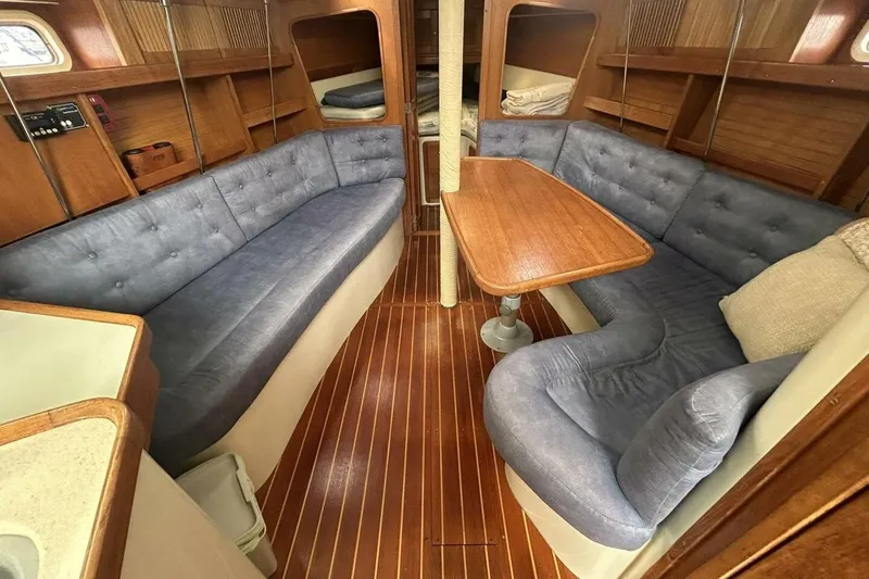 Slide: The Image of Interior of a 1995 Catalina 320 sailboat with blue cushioned seating and wooden table. - 18