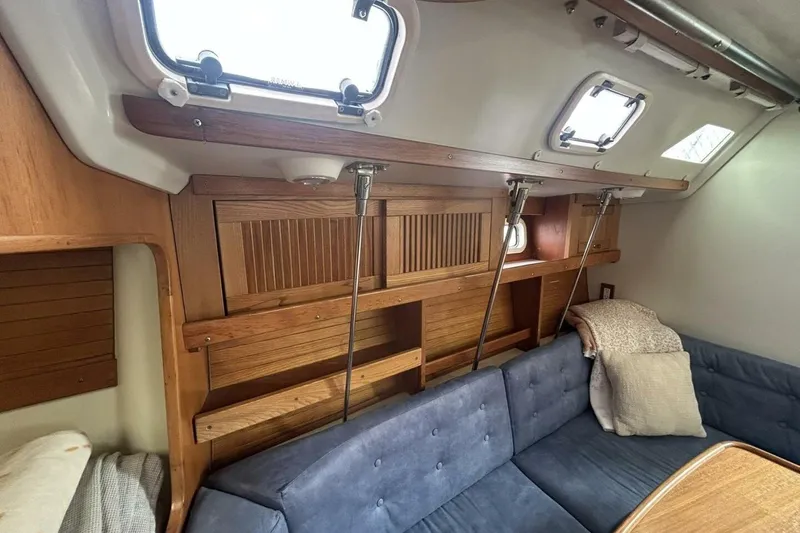 Slide: The Image of Interior of a 1995 Catalina 320 sailboat with wooden cabinetry and blue seating. - 22