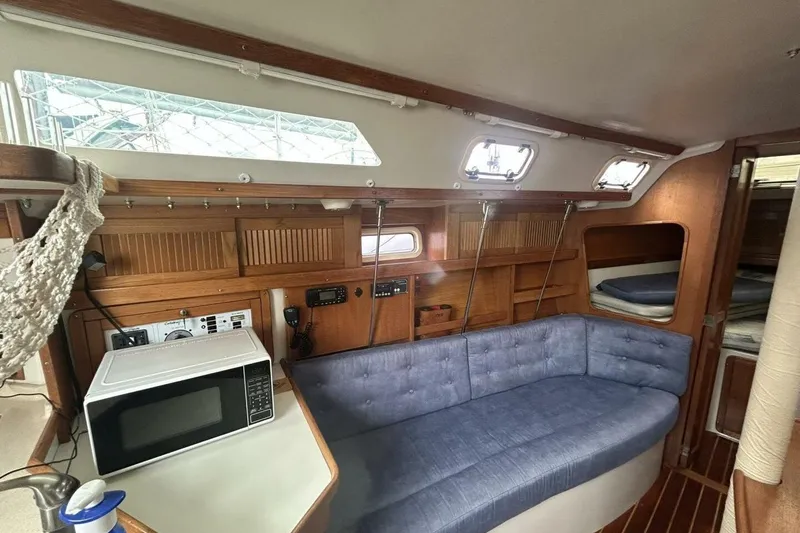 Slide: The Image of Interior of a 1995 Catalina 320 sailboat with blue seating and a microwave. - 23