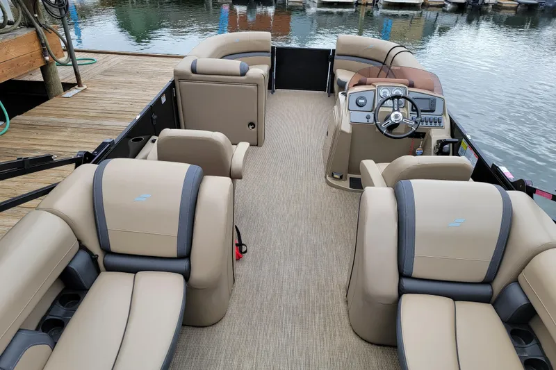 Slide: The Image of 2024 Starcraft EXS 3 pontoon boat interior with beige seating and modern dashboard. - 3