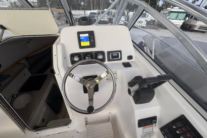 Slide: The Image of Century 2400 Walk-Around 2006 boat helm with steering wheel and navigation controls. - 14
