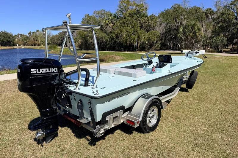 Slide: The Image of 2023 East Cape 18 EVO X boat with Suzuki engine on a grassy lakeside. - 2