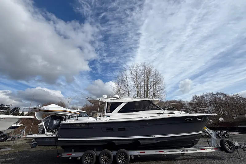 The Image of 2023 Cutwater C-32 Coupe boat on trailer under cloudy sky. - 0