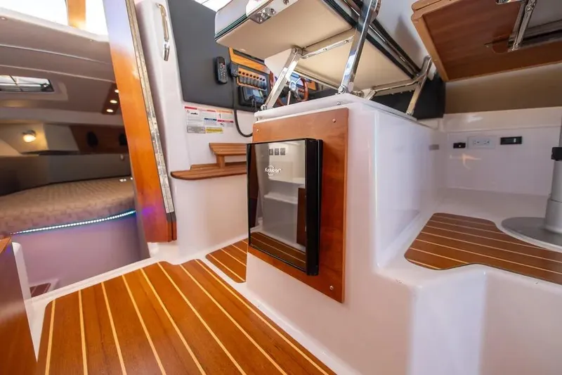 Slide: The Image of Interior of 2023 Cutwater C-32 Coupe boat with wood flooring and compact fridge. - 30